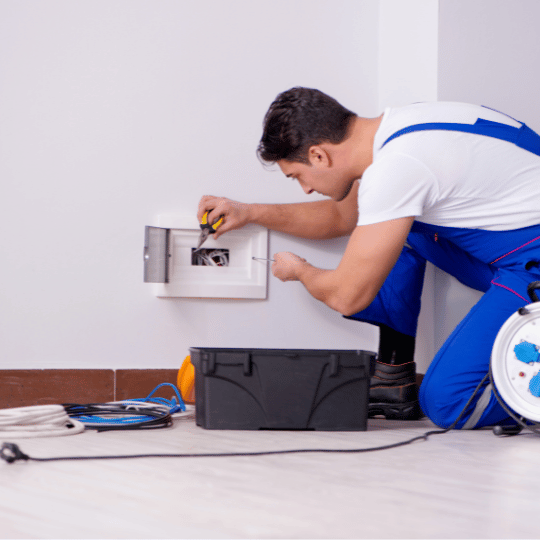 Electrician in blue overalls working on a power socket